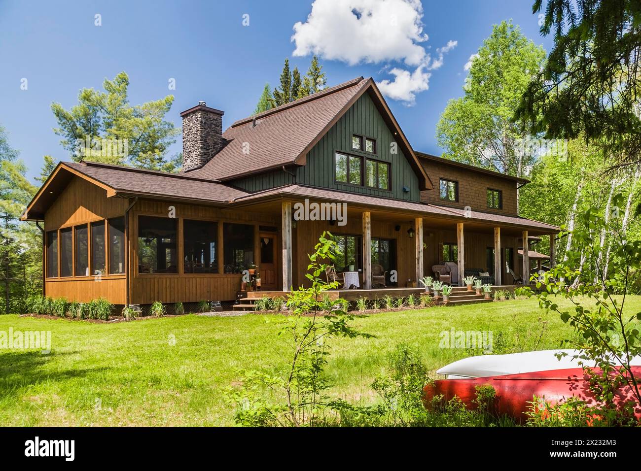 Vista posteriore di legno di abete rosso e verde e rivestimento in legno di cedro certificato LEED Country Home con veranda a fine primavera, Quebec, Canada Foto Stock