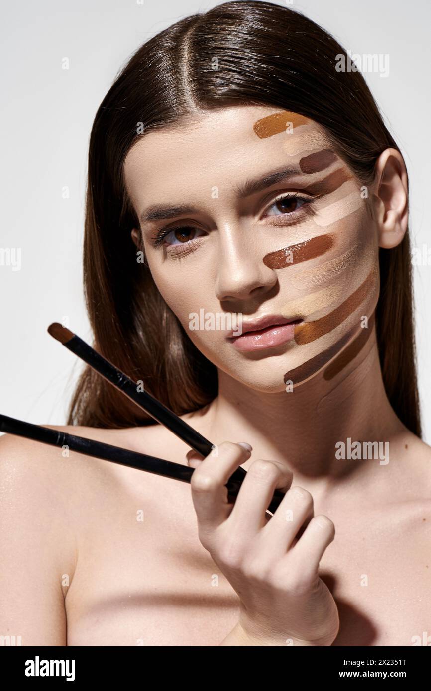 Donna sofisticata con vari pennelli per il trucco sul viso, che creano un look creativo e artistico con fondazioni. Foto Stock