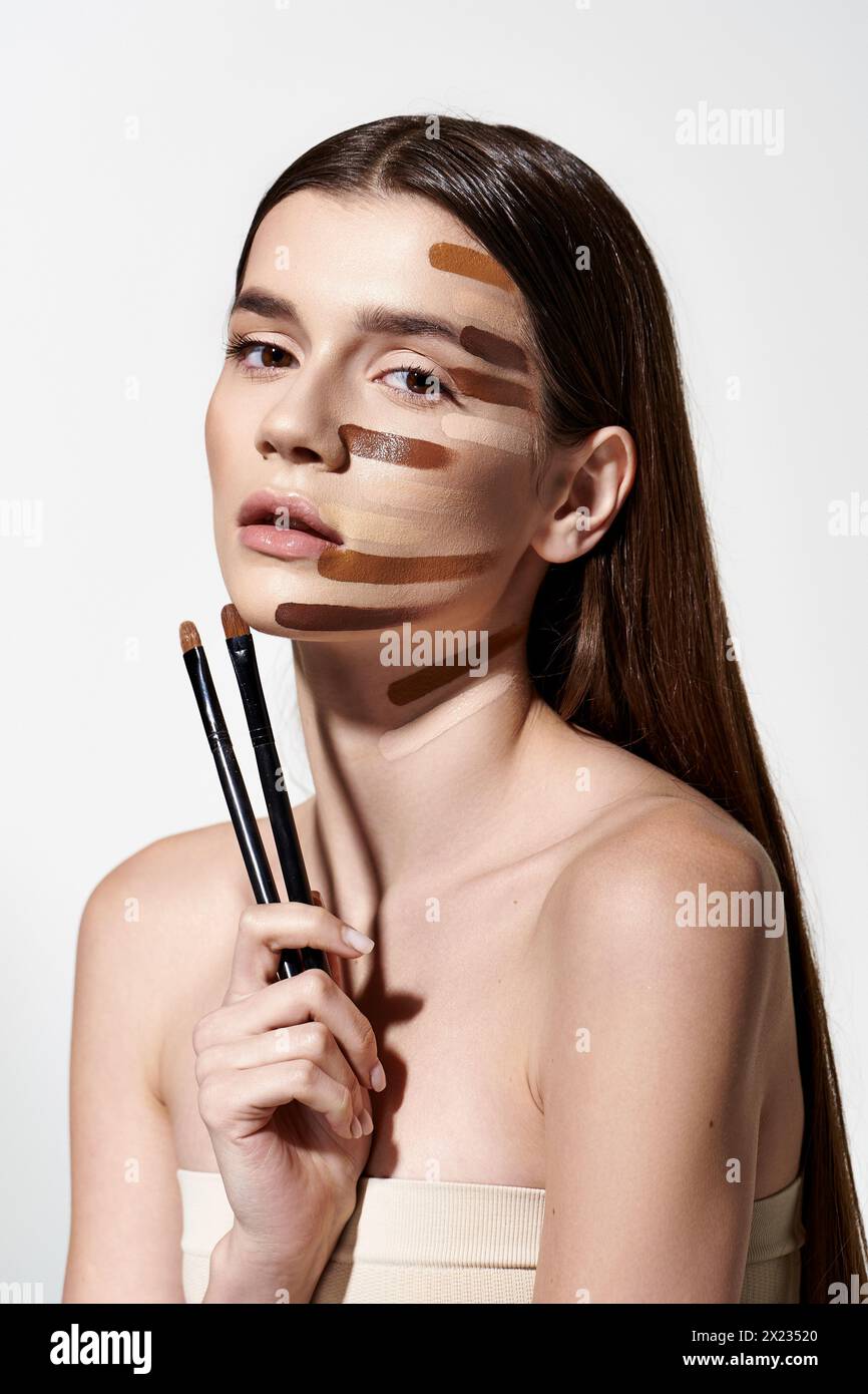 giovane donna con pennelli per il trucco e tratti di trucco sul viso, creando un look creativo e artistico con fondazioni. Foto Stock