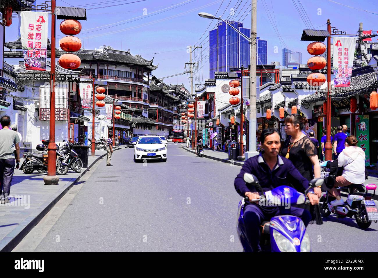 Passeggia attraverso Shanghai per raggiungere le attrazioni turistiche, Shanghai, Cina, Asia, la vivace strada cittadina con la tradizionale architettura cinese e uno scooter Foto Stock