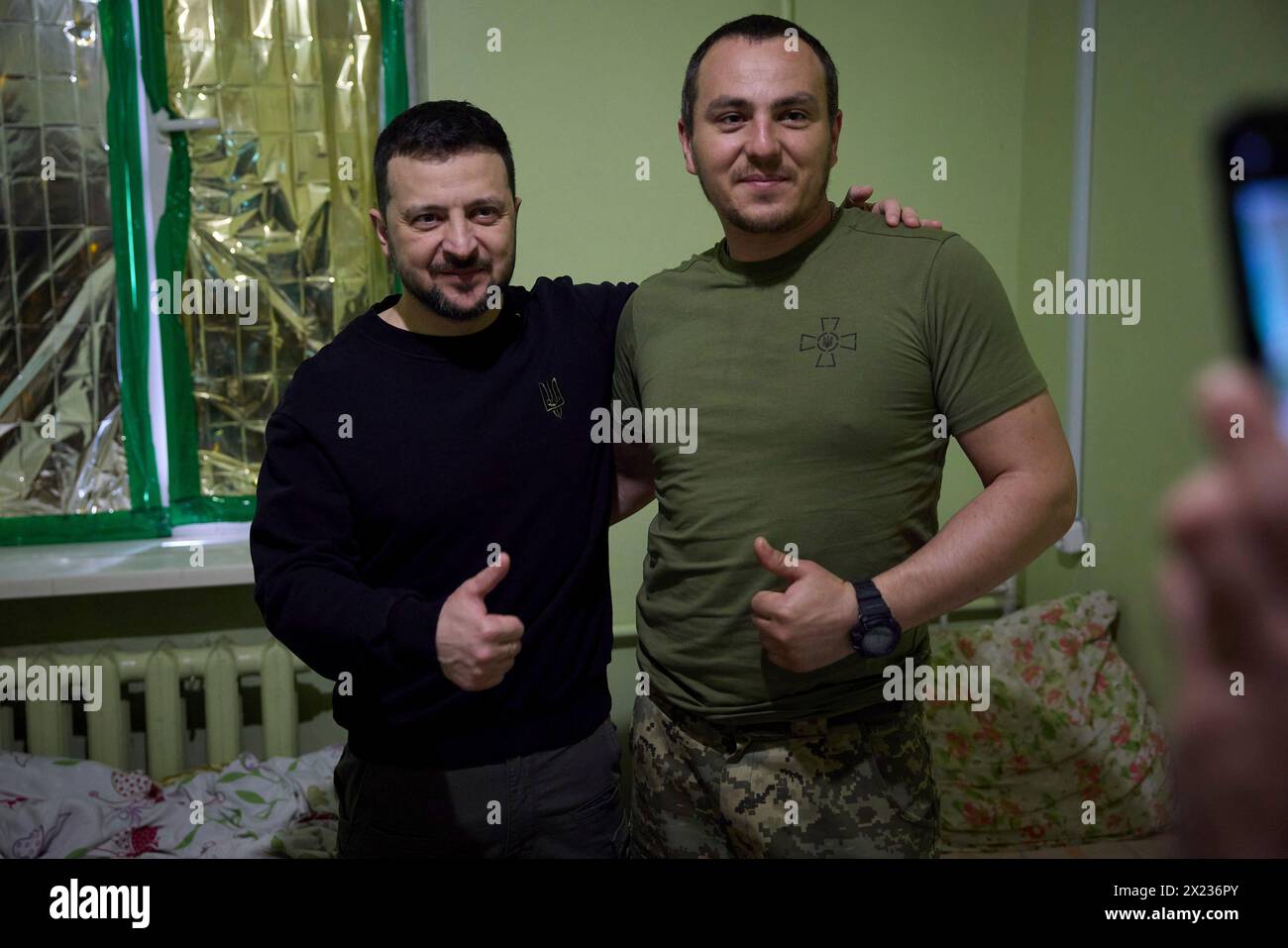 Slovyansk, Ucraina. 19 aprile 2024. Il presidente ucraino Volodymyr Zelenskyy, a sinistra, posa per un selfie con un soldato ferito della 95a brigata d'assalto aerea separata durante una visita a un ospedale militare nella regione del Donbas, 19 aprile 2023 a Slovyansk, Oblast di Donetsk, Ucraina. Credito: Handout/Ufficio stampa presidenziale ucraino/Alamy Live News Foto Stock