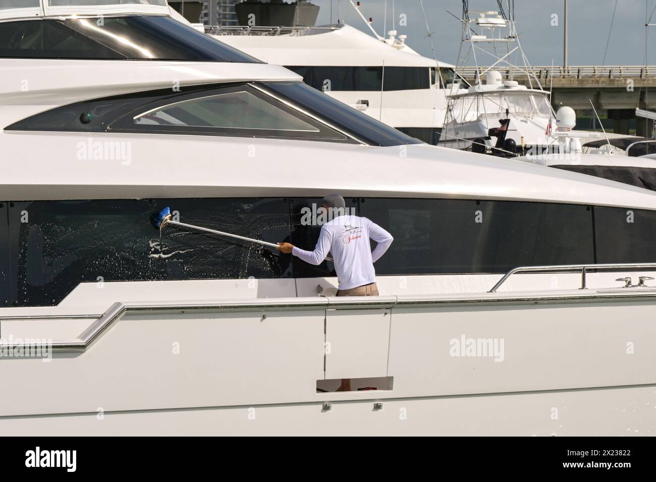 Miami, Florida, USA - 1 dicembre 2023: Membro dell'equipaggio di uno yacht di lusso che pulisce i finestrini con una spazzola Foto Stock