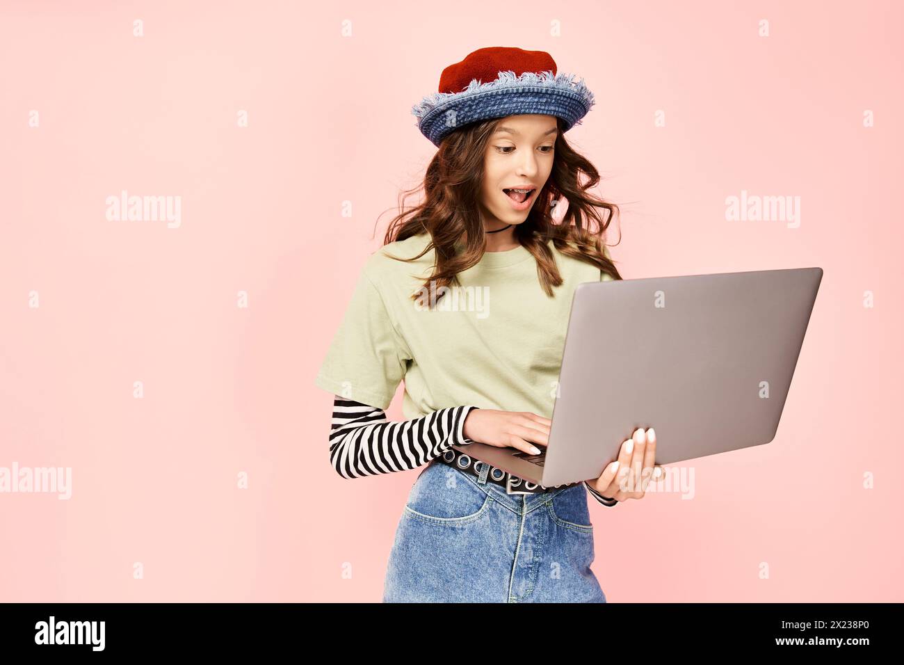 Un'adolescente elegante posa con sicurezza un notebook, indossando un cappello alla moda. Foto Stock