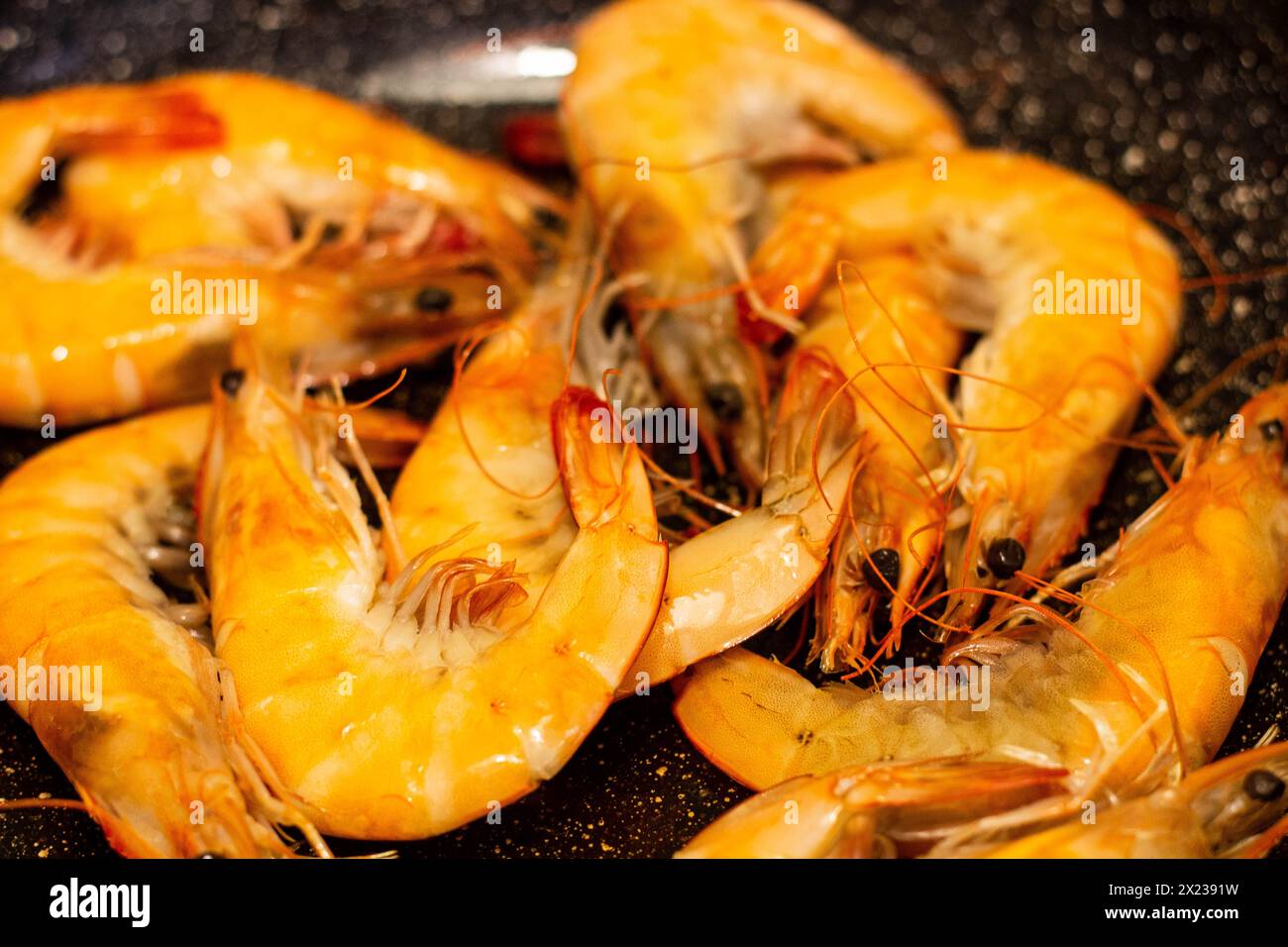 Prova l'eccellenza culinaria con succulenti gamberi sfrigolanti in padella. Deliziatevi con l'aroma e il sapore del pesce appena cucinato, pronto per essere tantaliz Foto Stock