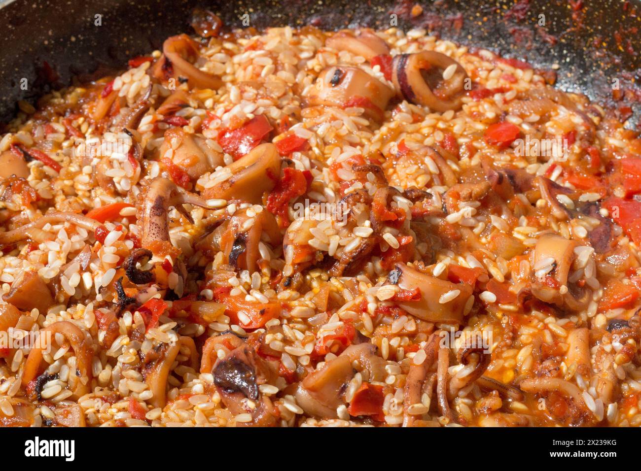 Assisti al momento cruciale mentre il riso si unisce al sofrito aromatico, esaltando l'essenza della tradizionale paella spagnola Foto Stock