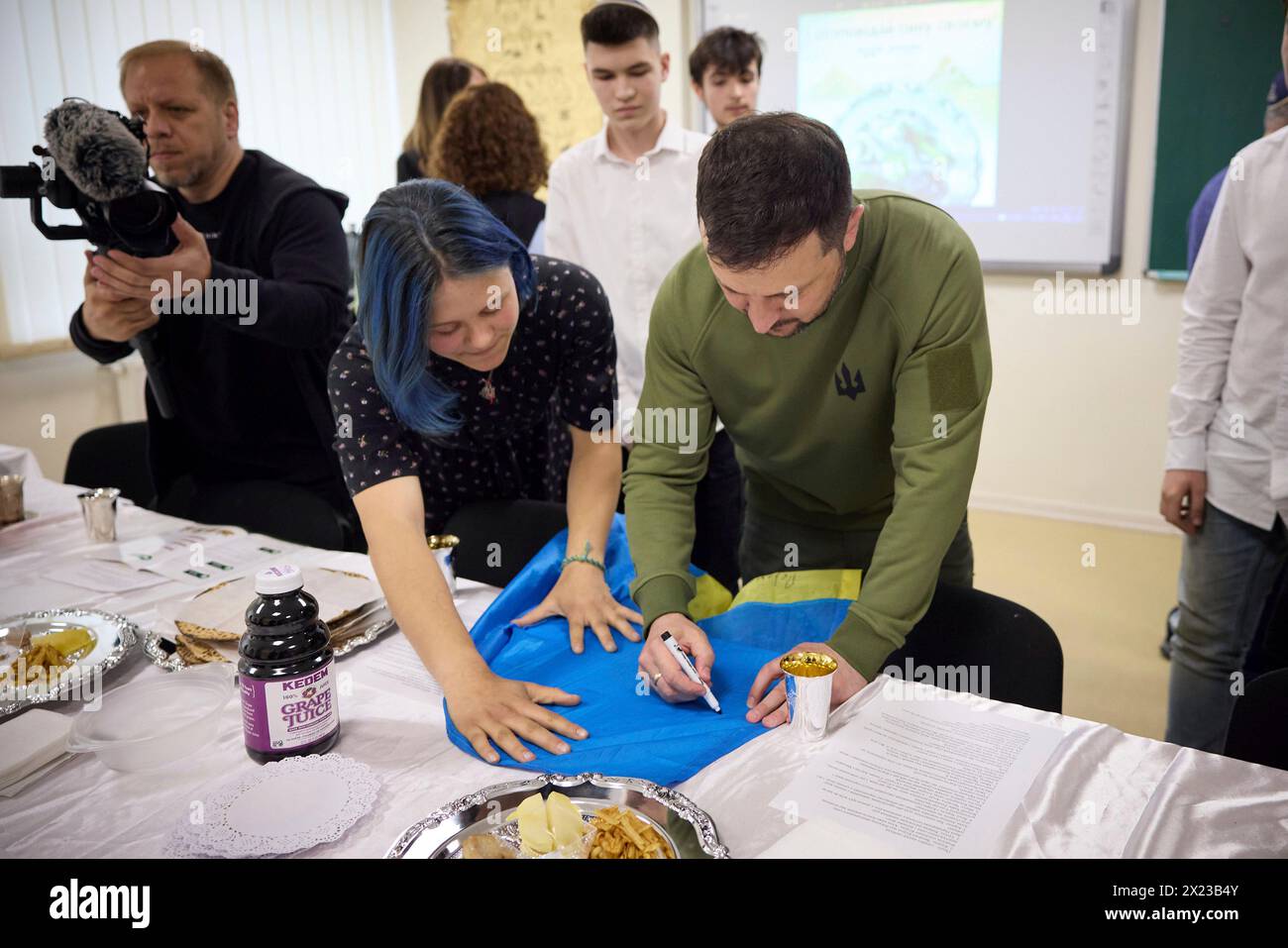 Kiev, Ucraina. 18 aprile 2024. Il presidente ucraino Volodymyr Zelenskyy, a sinistra, autografa una bandiera Ucraina durante una visita alla scuola di Shchastia gestita dal movimento Chabad-Lubavitch, 18 aprile 2024 a Kiev in Ucraina. Credito: Handout/Ufficio stampa presidenziale ucraino/Alamy Live News Foto Stock