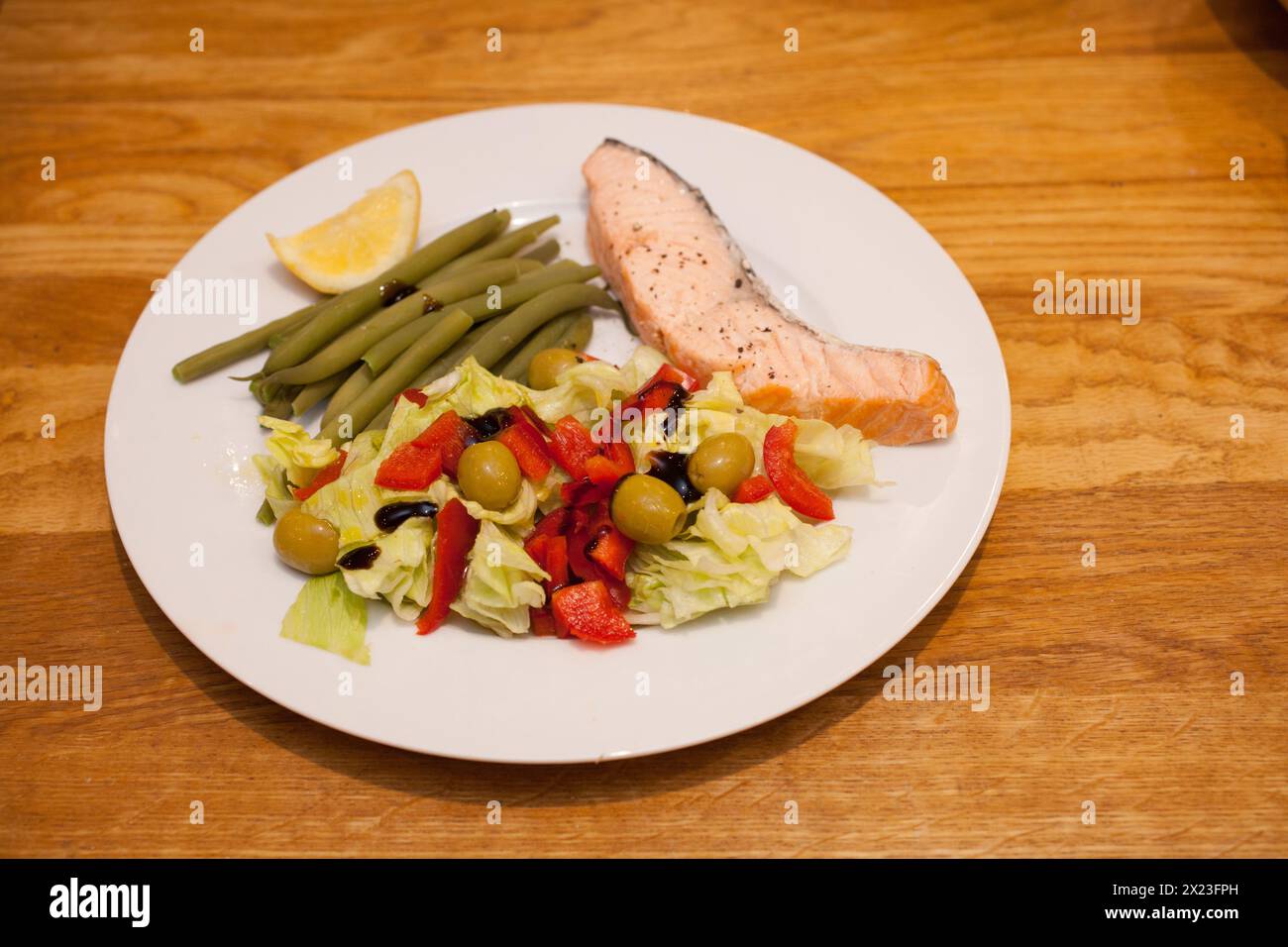 Un piatto di salmone in camicia, fagioli verdi e un'insalata fresca con peperoni rossi e olive Foto Stock