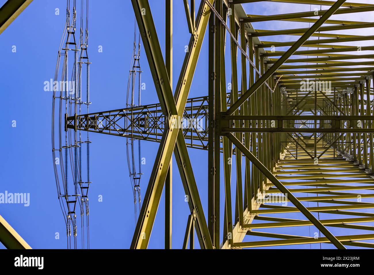 Struttura in acciaio complessa con capriate e sostegni trasversali di un pilone ad alta tensione con sospensione per linee elettriche viste dal basso Foto Stock