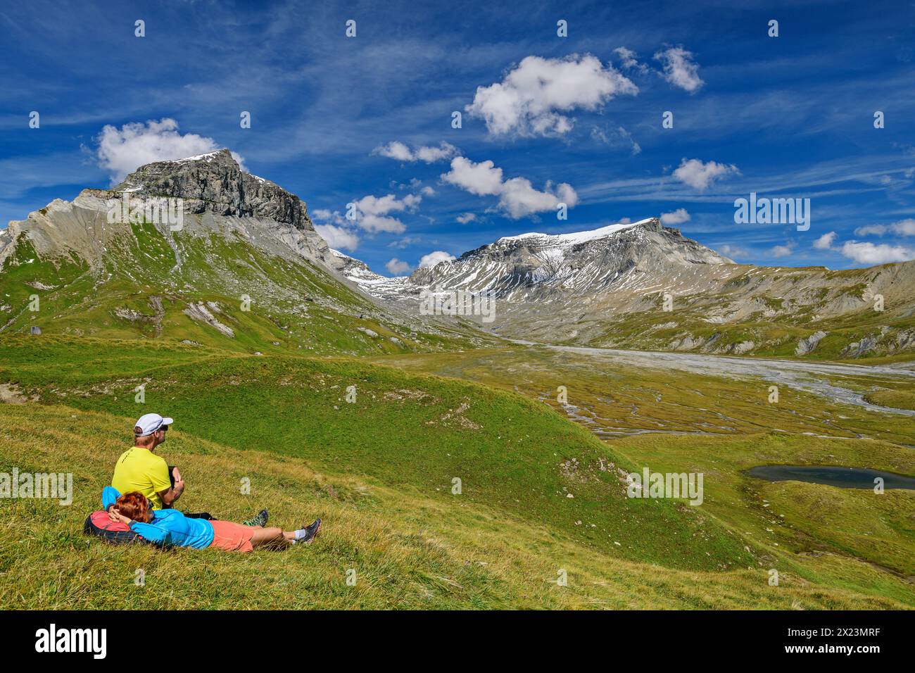 Uomo e donna che camminano seduti nel prato e guardano Atlante e Trinserhorn, Oberer Segnesboden, Tectonic Arena Sardona, Glarus Thrust, UNESCO World N Foto Stock