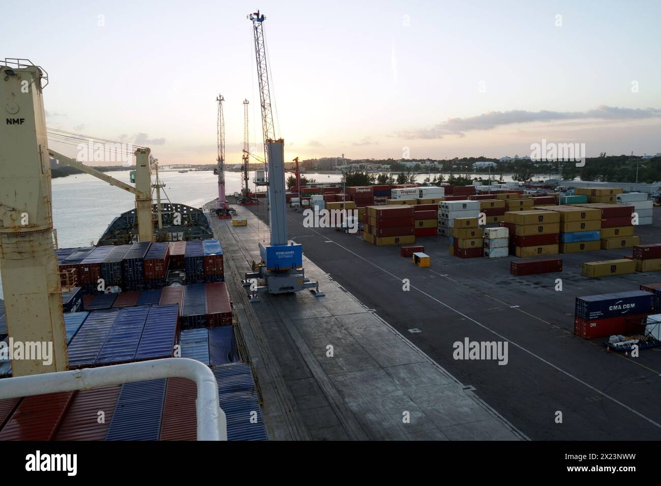 Nave portacontainer dotata di gru all'alba durante le operazioni di carico e scarico mediante gru mobili. Foto Stock