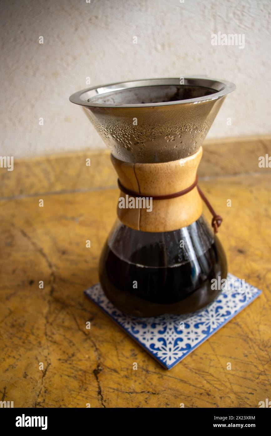 Versare il bicchiere sulla macchina per il caffè su piastrelle in ceramica. Shot verticale, completo, nessuno, versare sulla macchina per il caffè con caffè appena estratto Foto Stock
