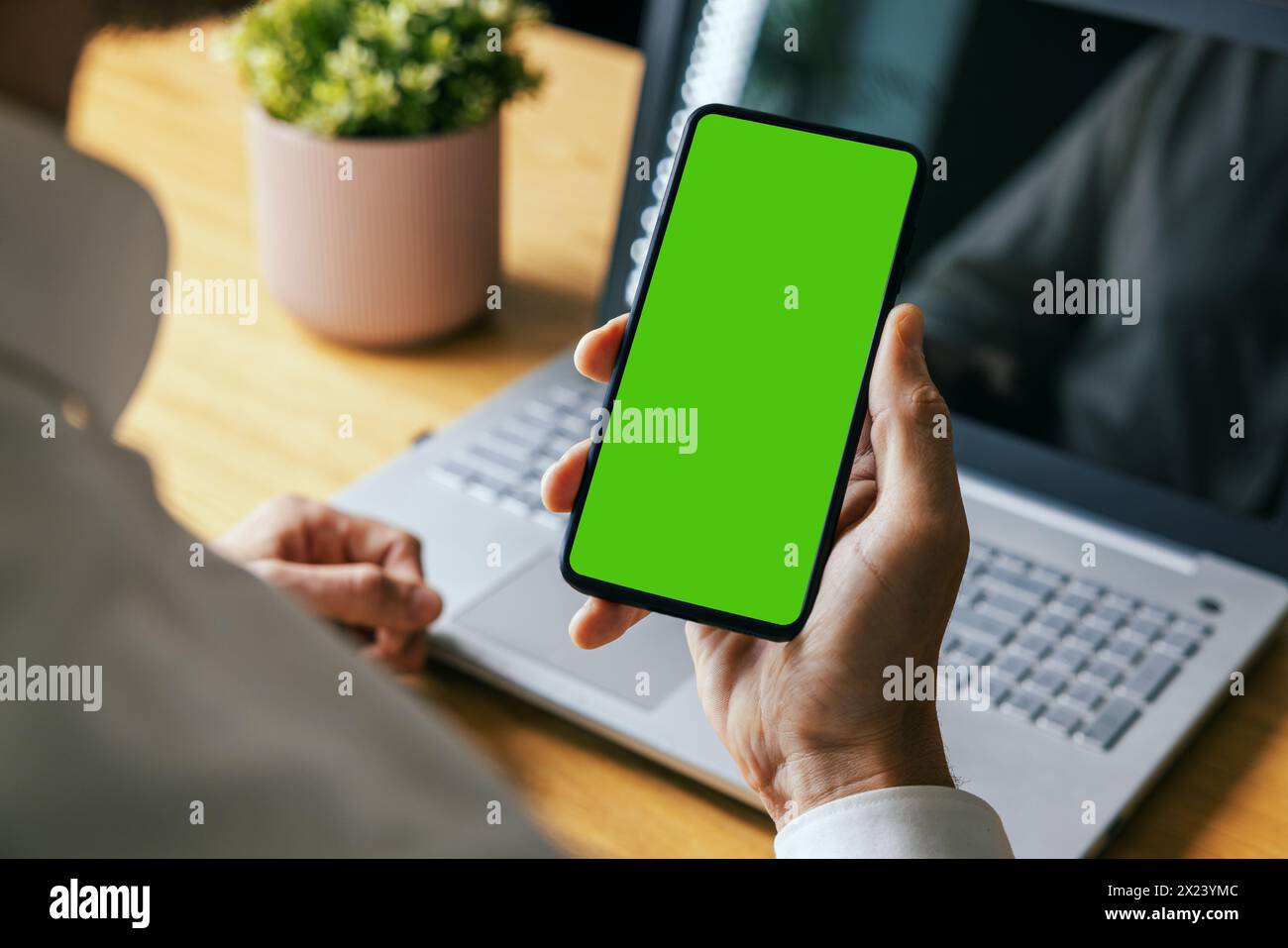 uomo che tiene in mano il telefono cellulare con schermo verde vuoto. modello di mockup Foto Stock