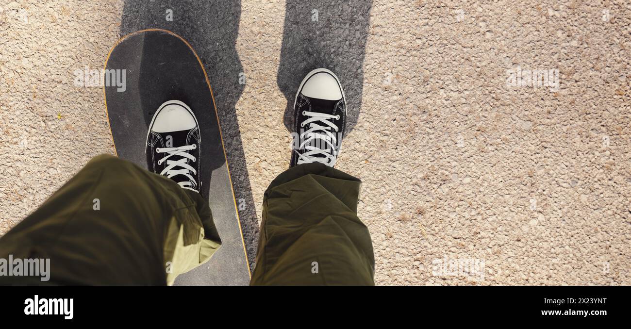 uomo in sella a uno skateboard su asfalto cittadino. skateboard su strada. Punto di vista, banner con spazio di copia Foto Stock
