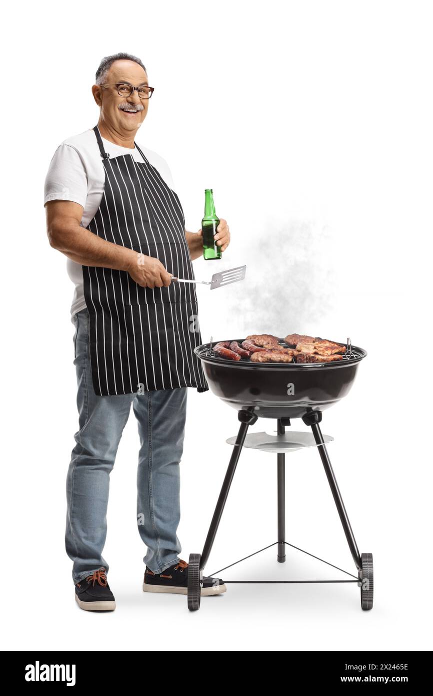 Uomo maturo che tiene in mano un utensile da cucina e una bottiglia di birra e carne alla griglia su un barbecue isolato su sfondo bianco Foto Stock