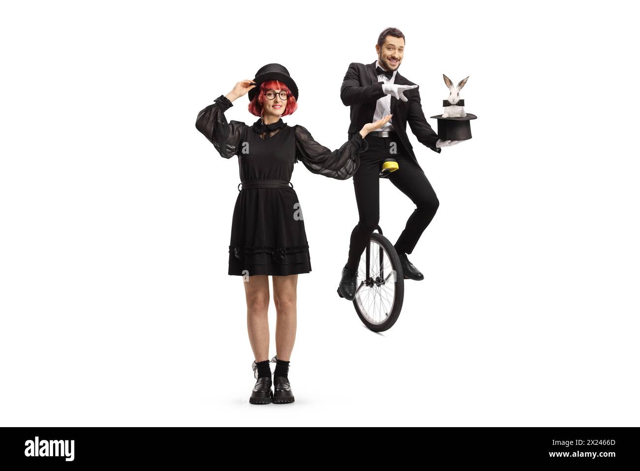 Donna che presenta un mago con un cappello e un coniglio su un monociclo isolato su sfondo bianco Foto Stock