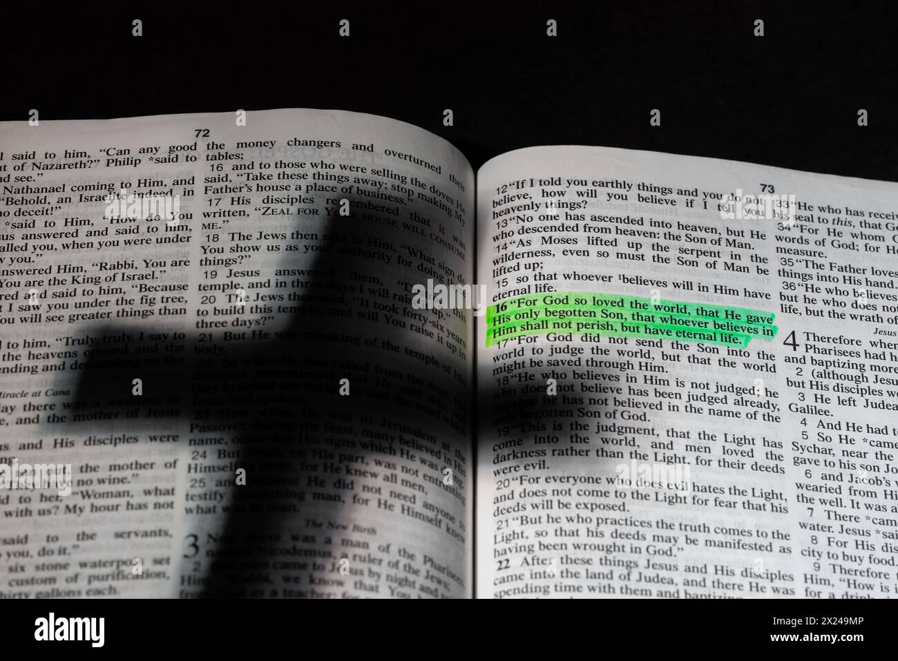 L'ombra di una croce su una Bibbia aperta con il versetto Giovanni 3:16 evidenziato. Foto Stock