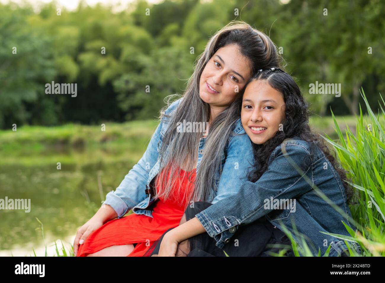 Primo piano di una giovane madre latina e di sua figlia che guardano e sorridono felicemente Foto Stock