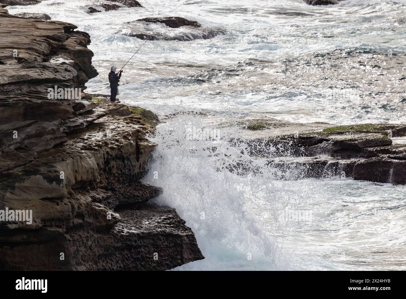 Fiherman pesca da rocce in mare pericoloso Foto Stock