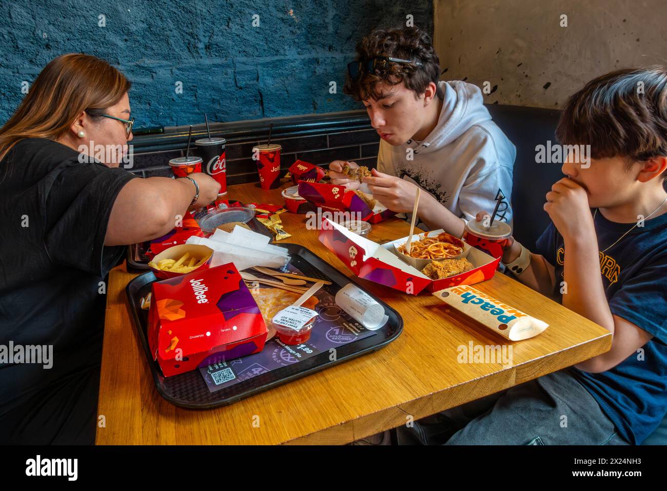 Una famiglia condivide un pasto a base di pollo fritto in un ristorante Jollibee a Reading, Regno Unito Foto Stock