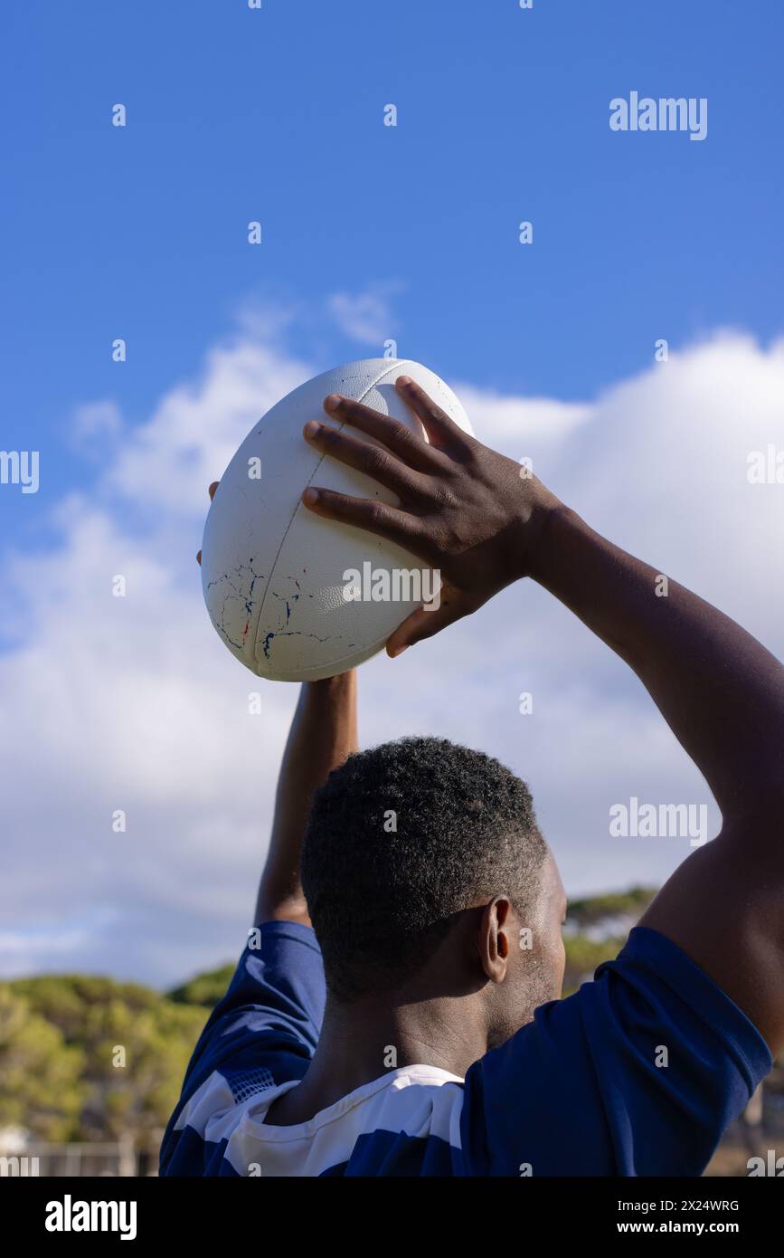 Giovane atleta afroamericano con in mano una palla da rugby, pronto a lanciare, copia spazio Foto Stock