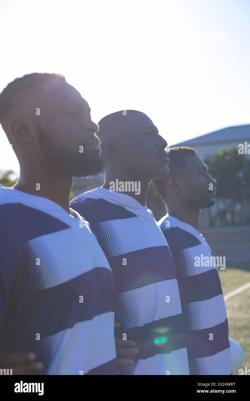 Tre atleti afroamericani maschili in abbigliamento sportivo a righe sono sul campo Foto Stock