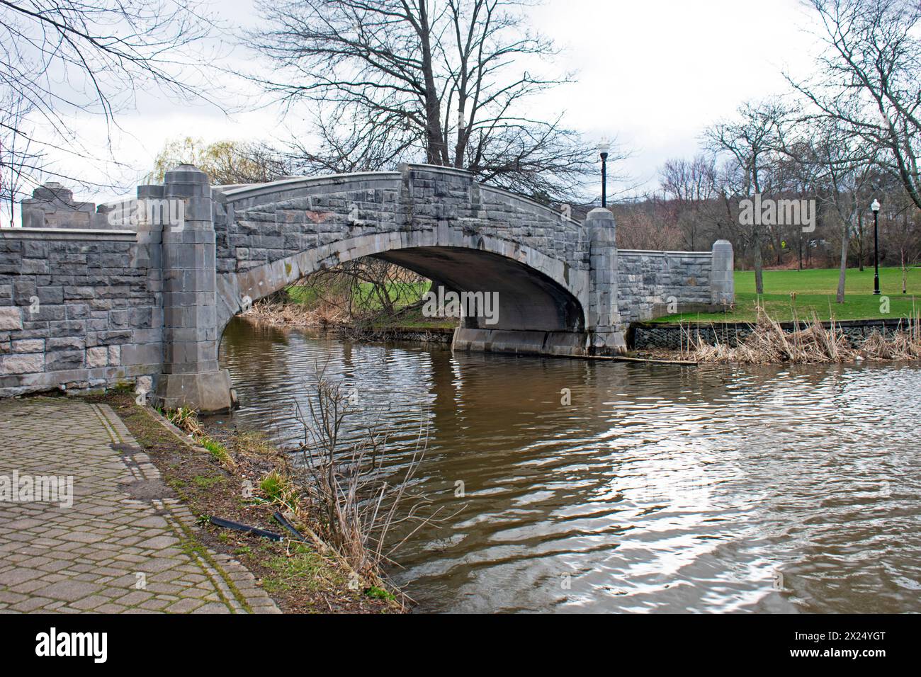 Grazioso ponte di pietra sul Lago di Verona nel Parco di Verona, Verona, New Jersey, in una giornata coperta all'inizio della primavera - 01 Foto Stock