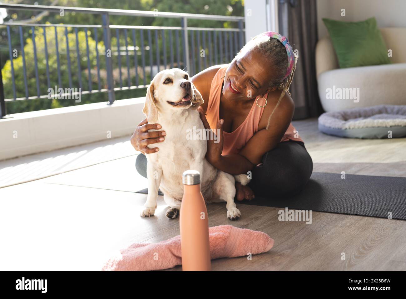 Una donna afroamericana anziana accarezza il suo cane a casa Foto Stock