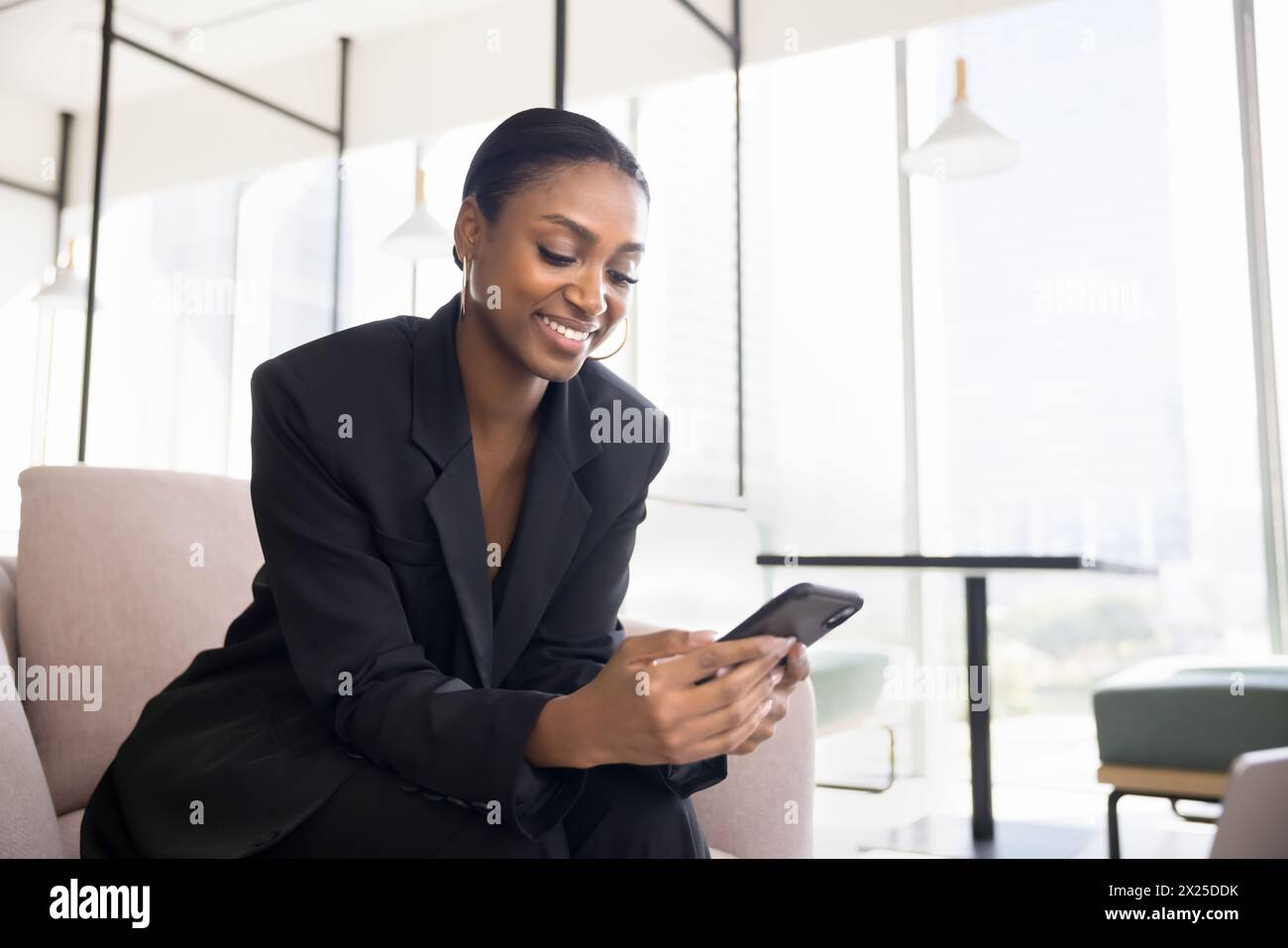 Positivo bella donna professionale nera che utilizza l'applicazione sul cellulare Foto Stock