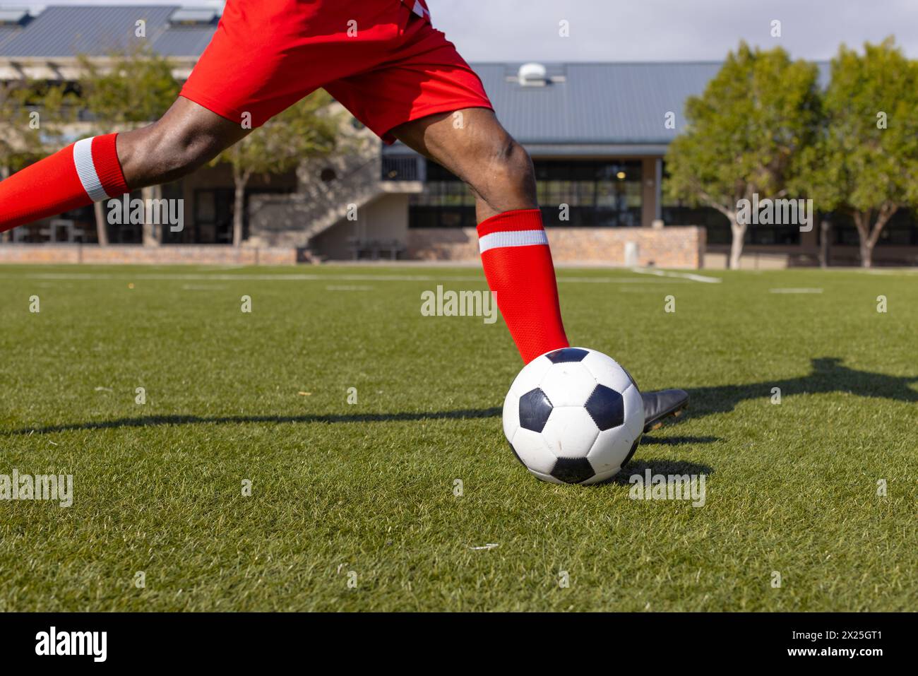 Un giovane atleta afroamericano che indossa il rosso gioca a calcio all'aperto Foto Stock