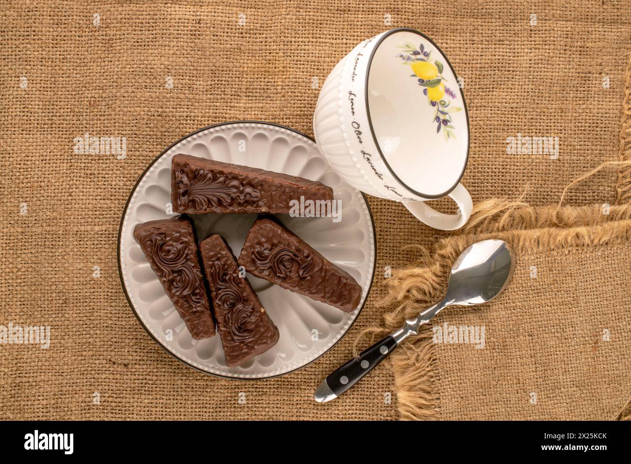 Quattro fette di torta al cioccolato con piatto in ceramica e tazza su un panno di iuta, vista dall'alto Foto Stock
