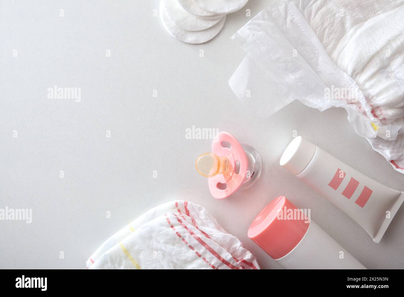 Accessori rosa per cambiare il pannolino e prendersi cura della pelle del bambino con crema e talco in polvere. Vista dall'alto. Foto Stock
