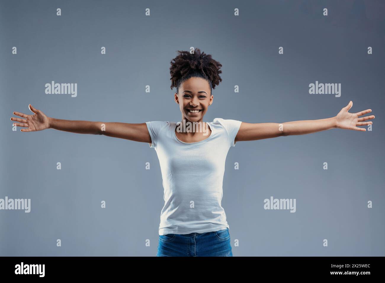 Giovane donna a braccia aperte con travi bianche di camicia, che offre un abbraccio in modo amichevole Foto Stock
