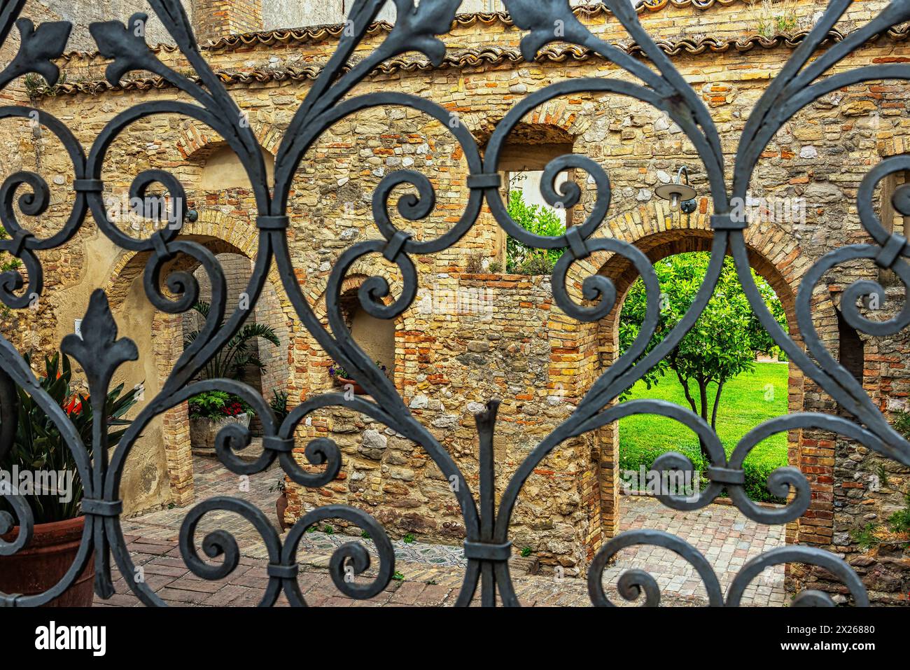 La recinzione in mattoni di terracotta che circonda il giardino napoletano e la porta in ferro battuto di Palazzo D'Avalos nella città di vasto. Vasto, Abruzzo, Italia Foto Stock