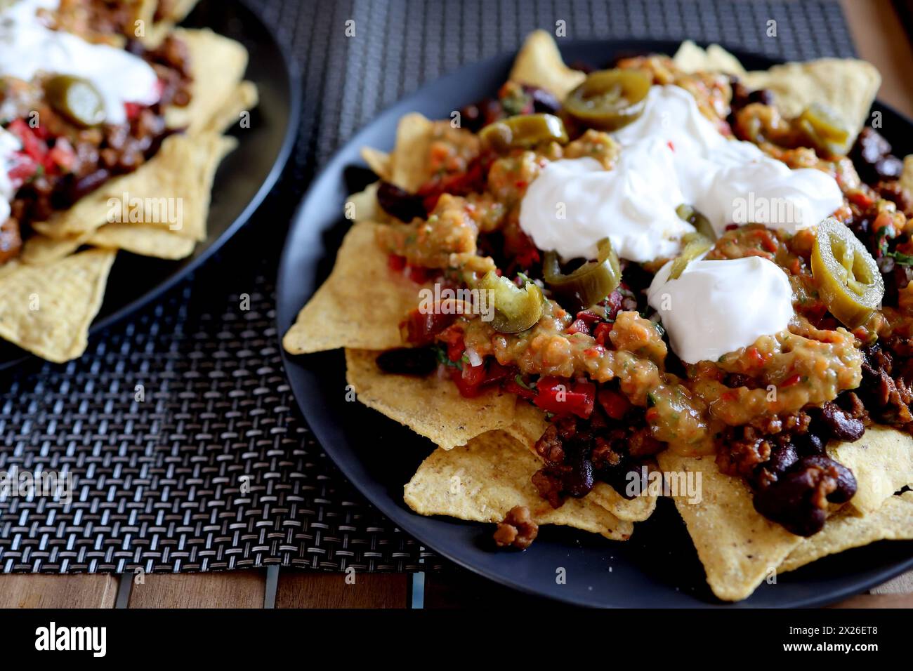 Piatto appetitoso su un piatto: Nachos di patatine di mais con carne macinata fritta e guacamole, fagioli, salsa, jalapenos vista dall'alto. Cucina messicana fatta in casa Foto Stock