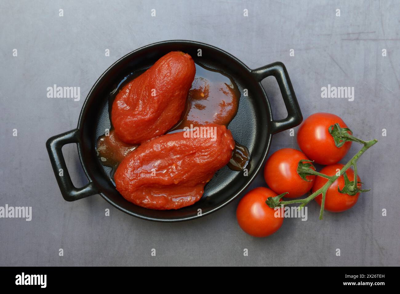 Pomodori interi in scatola in una pentola e pomodori Foto Stock
