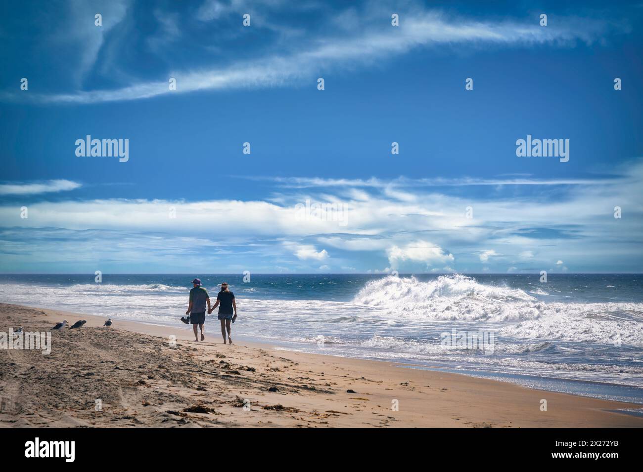 Un uomo e una donna non identificati camminano, mano nella mano, sulla sabbia di Imperial Beach, California. Foto Stock