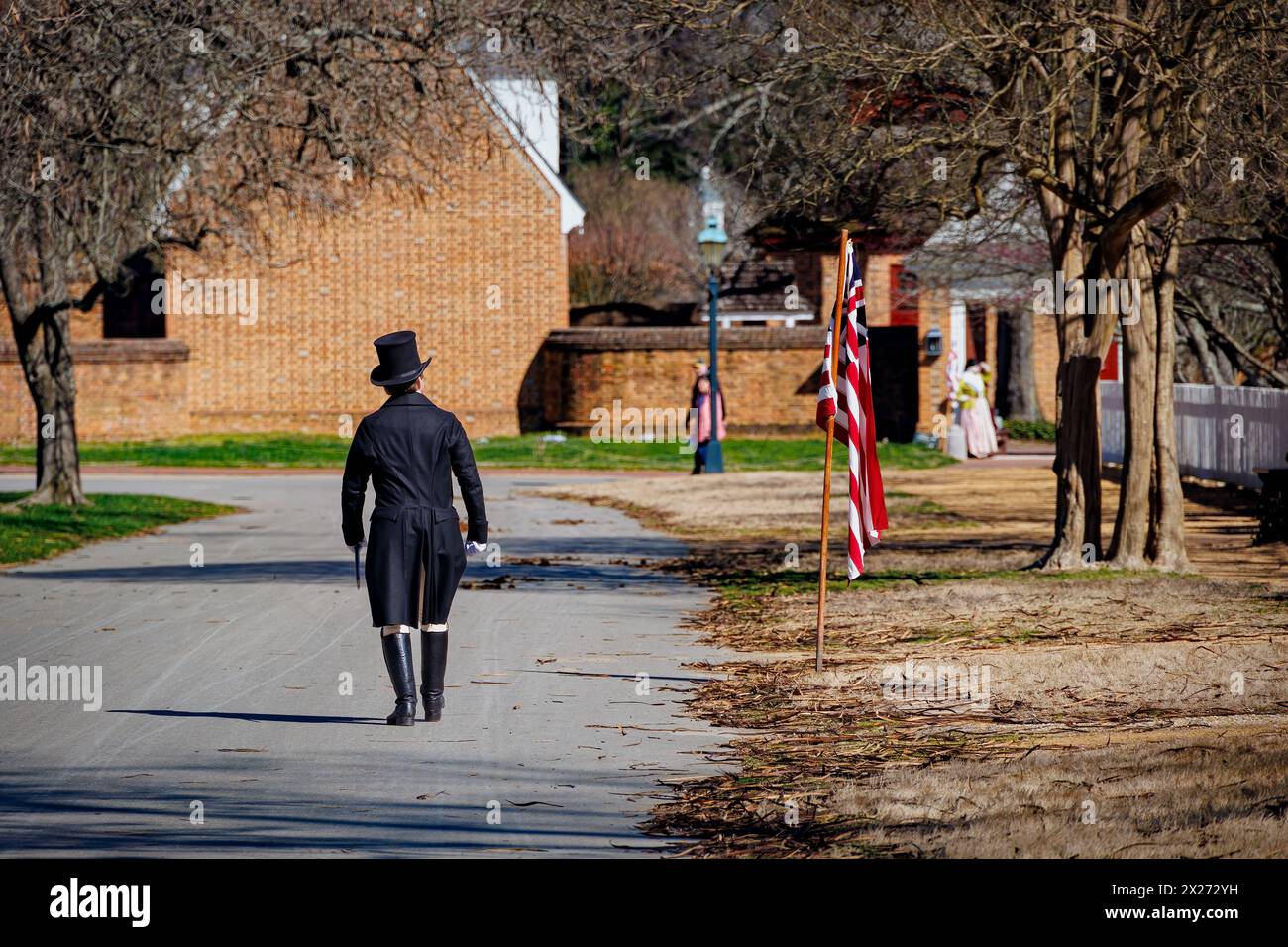 Un uomo con un cappello cammina per la strada, in abiti d'epoca, a Colonial Williamsburg, Virginia. Foto Stock