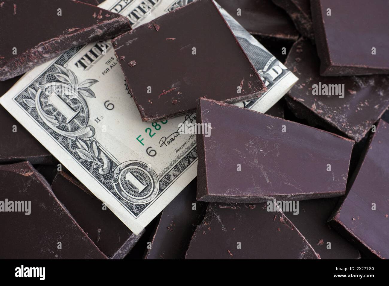 Banconota da un dollaro in una pila di pezzi di cioccolato. Concetto di prezzi del cioccolato. Foto Stock