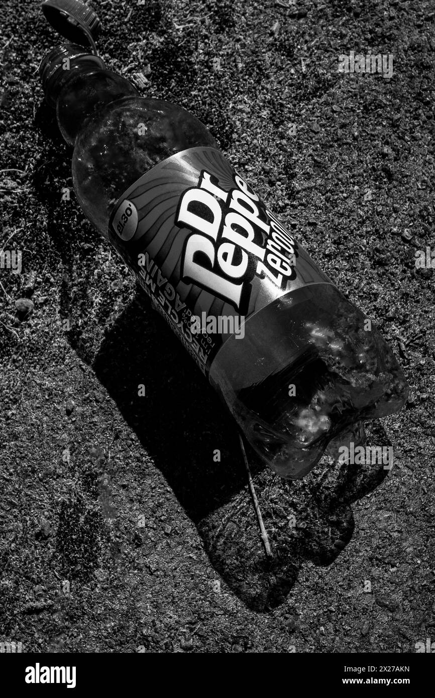Danni ambientali: Una grande bottiglia di plastica Dr. Pepper scaricata su un sentiero pubblico a Cardiff, Galles. Inquinamento. Lettiera. Immagine in bianco e nero. Foto Stock