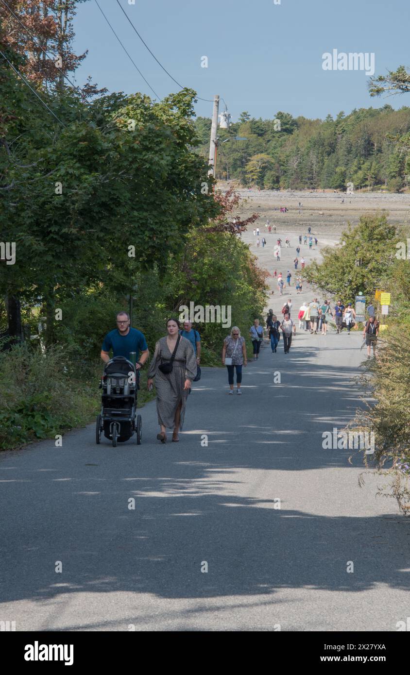 I turisti camminano su e giù per Bridge Street fino al bar di sabbia a Bar Harbor con la bassa marea. Mount dessert Island, Maine, Stati Uniti Foto Stock