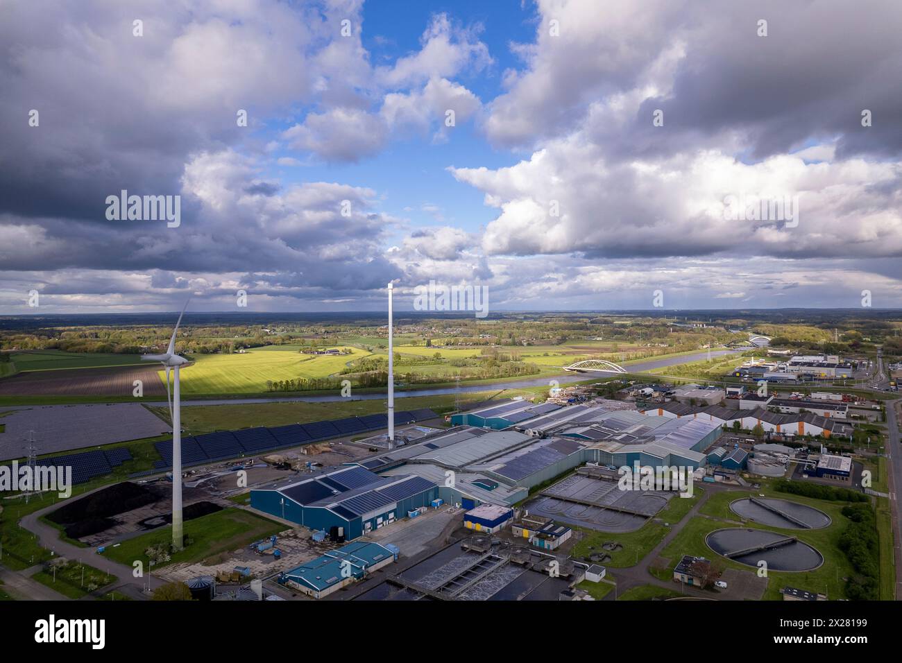 Primo piano di turbine eoliche, trattamento delle acque e impianto di bioenergia. Industria sostenibile nel paesaggio fluviale olandese contro il cielo spettacolare. Antenna circolare Foto Stock
