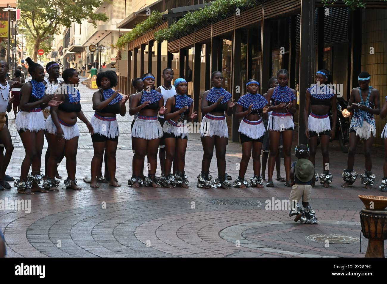 Gruppo di ragazzi e ragazze di colore in costume locale che eseguono una tipica danza africana nel centro di città del Capo, in Sudafrica Foto Stock