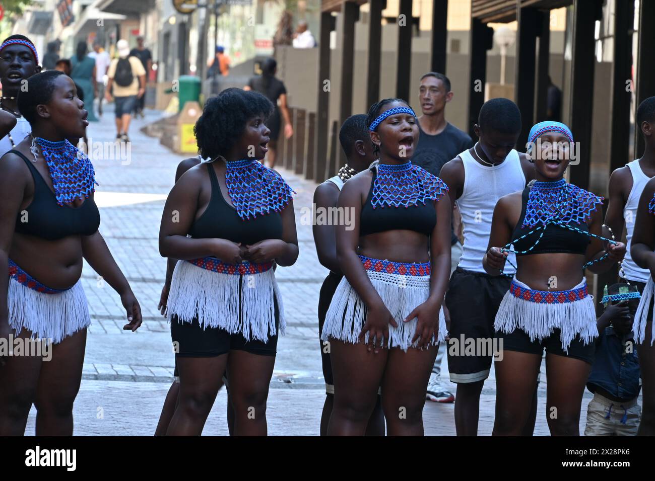 Gruppo di ragazzi e ragazze di colore in costume locale che eseguono una tipica danza africana nel centro di città del Capo, in Sudafrica Foto Stock