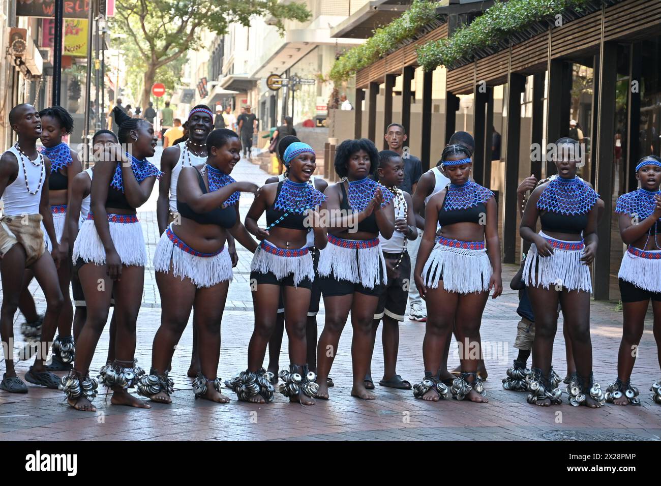 Gruppo di ragazzi e ragazze di colore in costume locale che eseguono una tipica danza africana nel centro di città del Capo, in Sudafrica Foto Stock