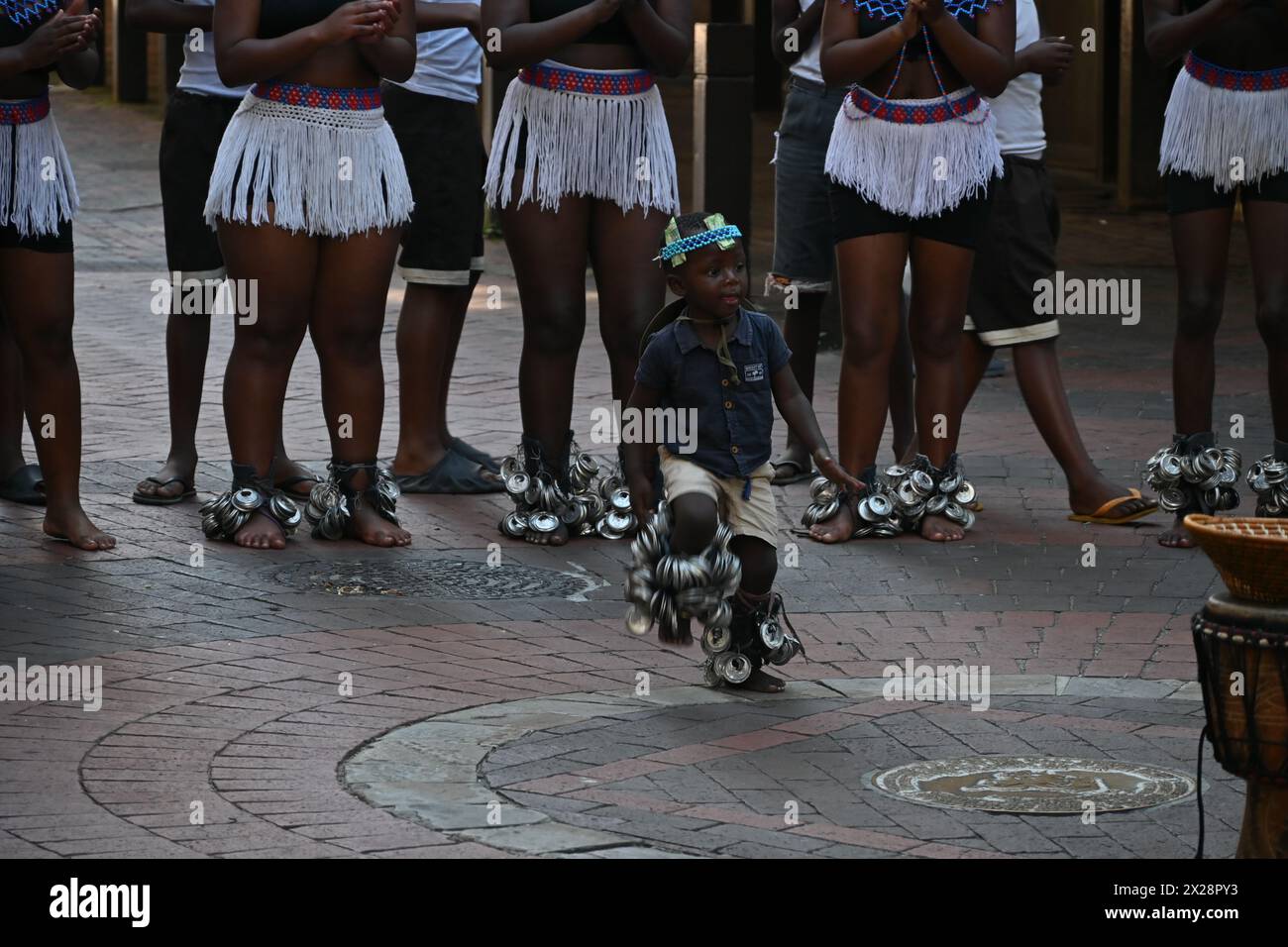 Un ragazzino nero in costume locale che esegue una tipica danza africana nel centro di città del Capo, in Sudafrica Foto Stock