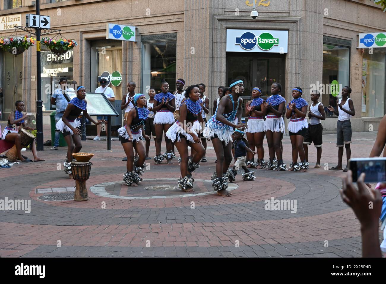 Gruppo di ragazzi e ragazze di colore in costume locale che eseguono una tipica danza africana nel centro di città del Capo, in Sudafrica Foto Stock