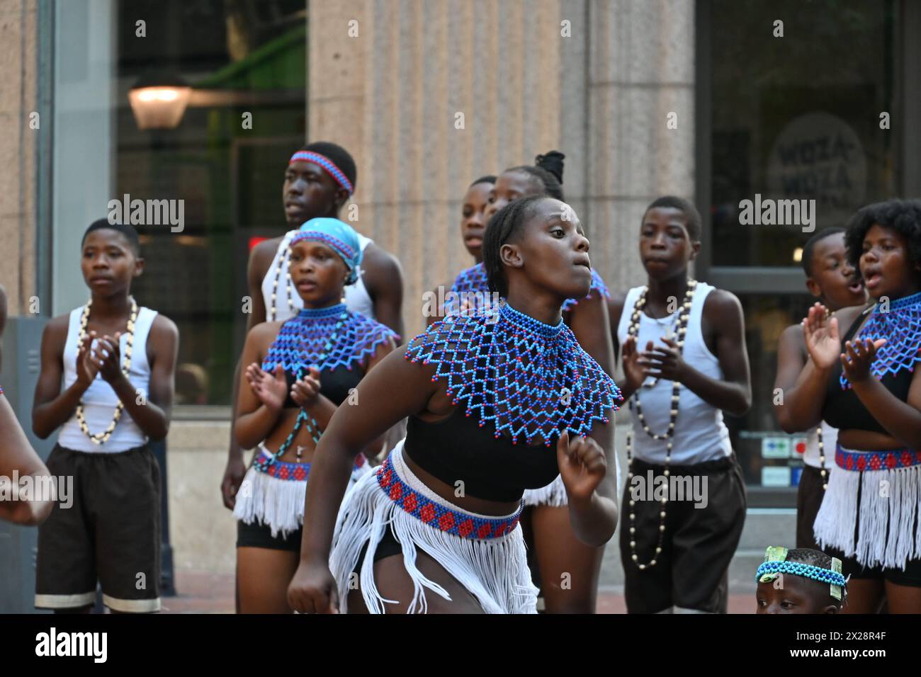 Gruppo di ragazzi e ragazze di colore in costume locale che eseguono una tipica danza africana nel centro di città del Capo, in Sudafrica Foto Stock