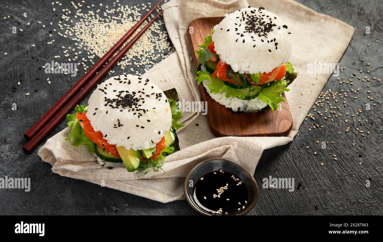 Sushi hamburger asiatico, salsa di soia, bacchetta su sfondo scuro. Cibo ibrido alla moda. Foto Stock