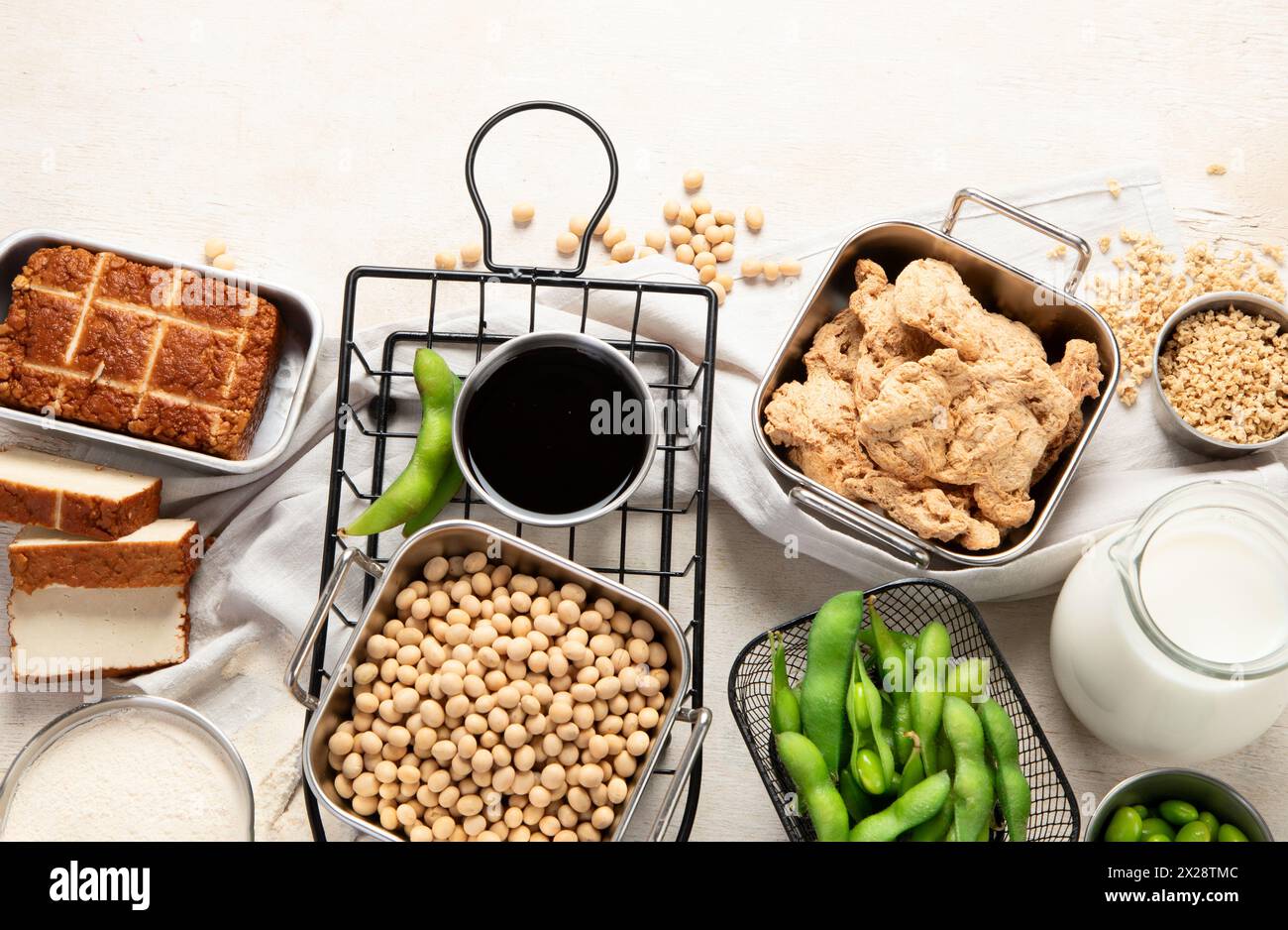 Vari prodotti di soia con semi di soia, tofu, salsa di soia e latte di soia su sfondo chiaro. Vista dall'alto. Copia spazio. Foto Stock