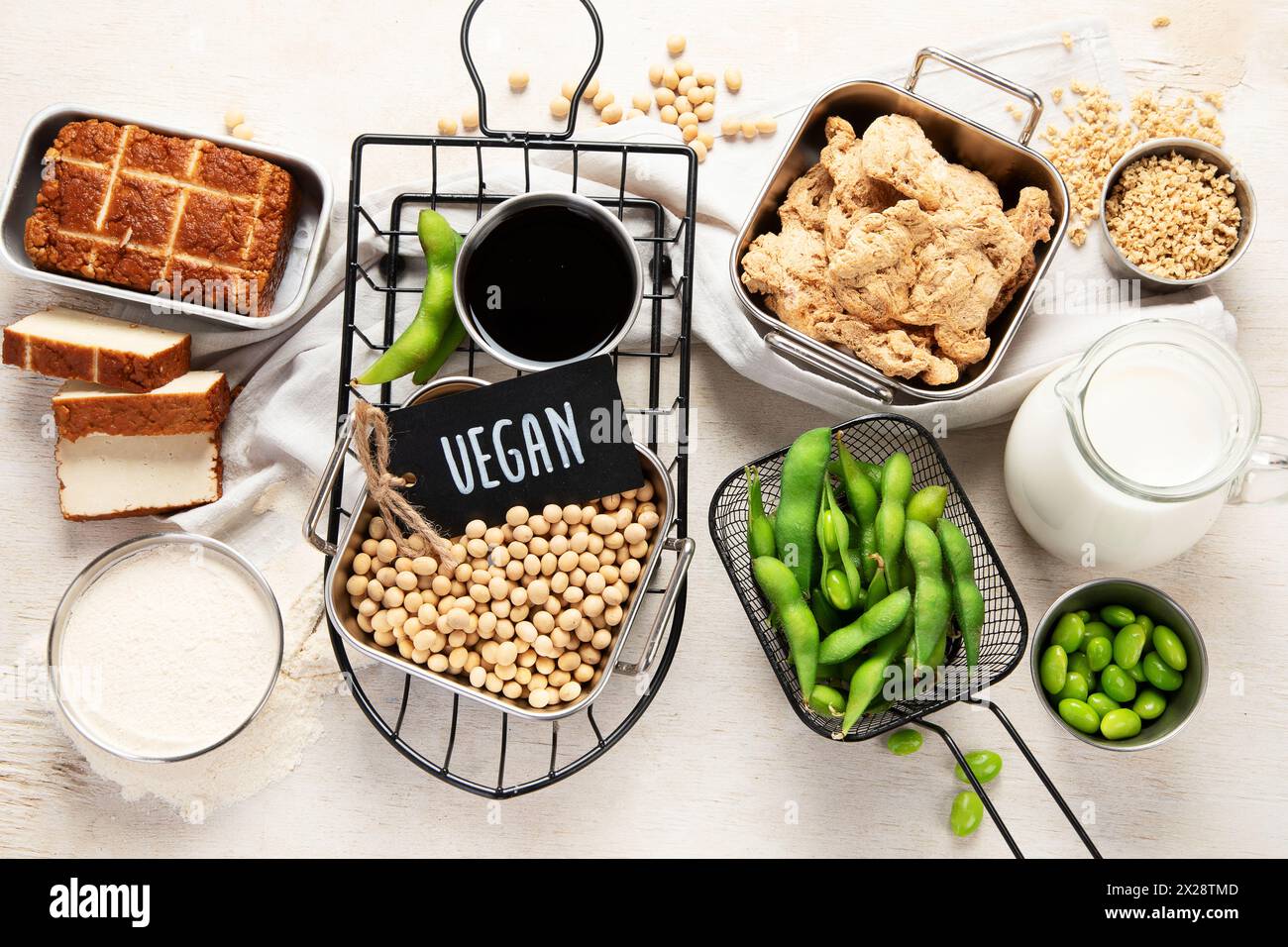 Vari prodotti di soia con semi di soia, tofu, salsa di soia e latte di soia su sfondo chiaro. Vista dall'alto Foto Stock